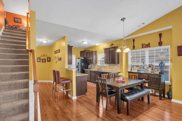 dining room featuring sink, vaulted ceiling, and light hardwood / wood-style floors