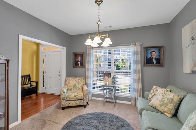 living area featuring carpet floors, a healthy amount of sunlight, and a chandelier