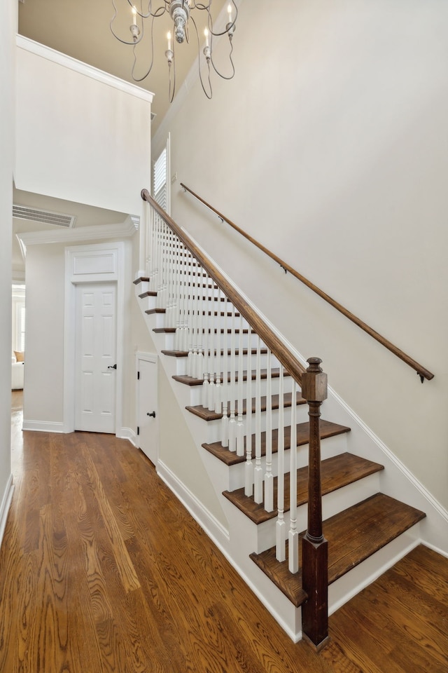 stairs featuring wood-type flooring and an inviting chandelier