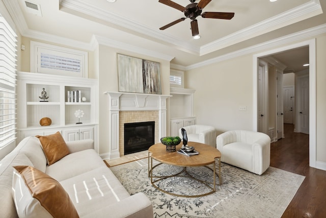 living room featuring a tile fireplace, ornamental molding, hardwood / wood-style flooring, and a healthy amount of sunlight