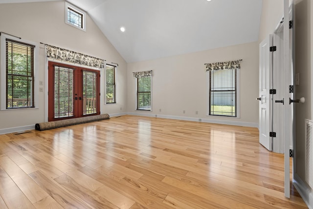 empty room with high vaulted ceiling, french doors, plenty of natural light, and light wood-style flooring