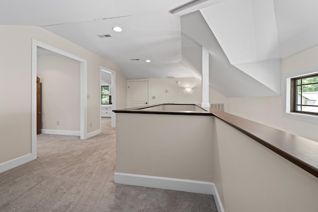 interior space featuring lofted ceiling, light carpet, visible vents, and baseboards