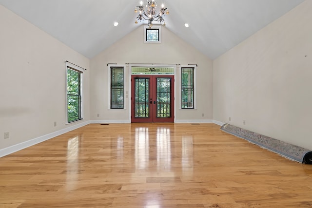 interior space featuring high vaulted ceiling, an inviting chandelier, light hardwood / wood-style flooring, and french doors