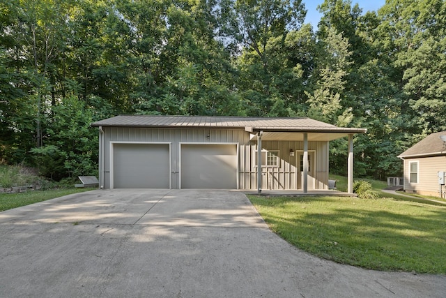 view of front of property with metal roof, a garage, an outdoor structure, board and batten siding, and a front yard