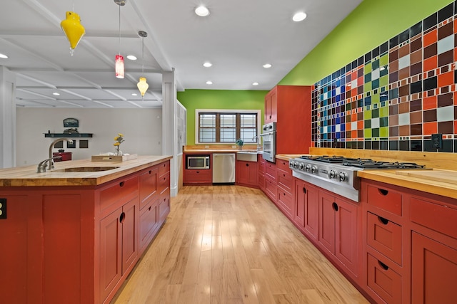 kitchen featuring wooden counters, appliances with stainless steel finishes, hanging light fixtures, and a sink