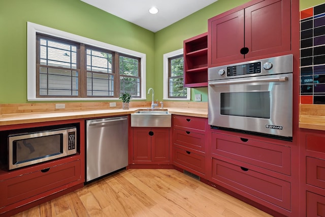 kitchen featuring butcher block countertops, stainless steel appliances, light wood-type flooring, open shelves, and a sink