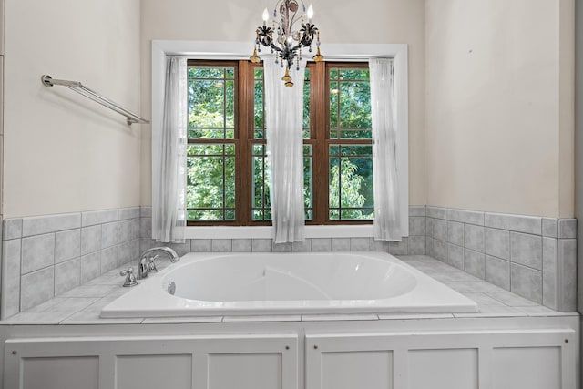 bathroom featuring an inviting chandelier, plenty of natural light, and a garden tub