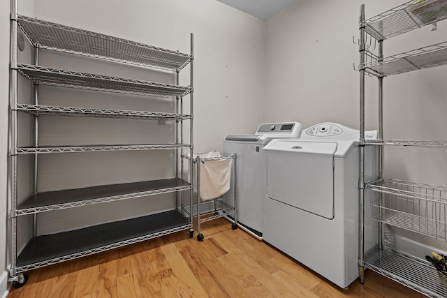 laundry area with laundry area, washing machine and dryer, and wood finished floors