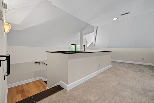 bonus room with vaulted ceiling and light carpet