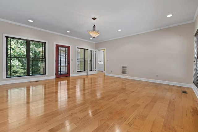empty room featuring baseboards, visible vents, crown molding, and light wood finished floors