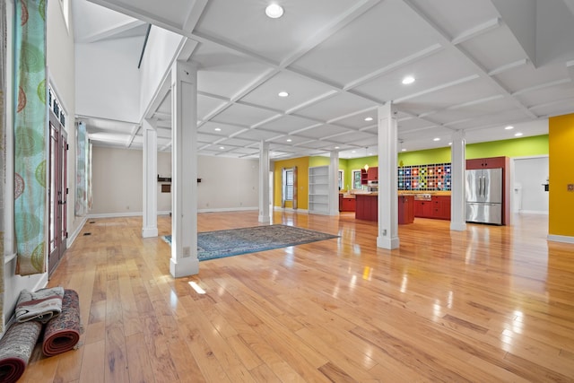 interior space featuring decorative columns, coffered ceiling, and light wood-style flooring