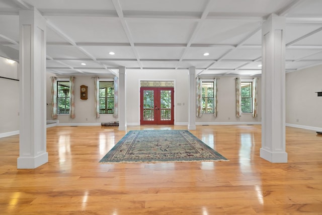 foyer featuring light wood finished floors, french doors, coffered ceiling, and decorative columns