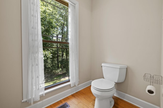 bathroom featuring toilet, baseboards, visible vents, and wood finished floors
