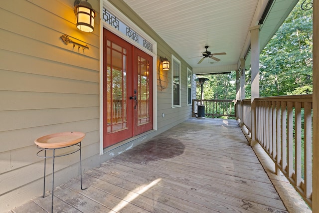 wooden deck with french doors, covered porch, and ceiling fan