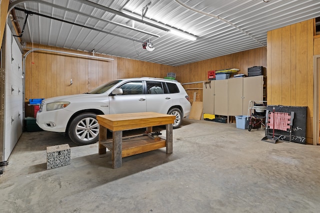 garage featuring a carport, wood walls, and a garage door opener