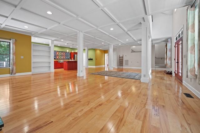 exercise room with baseboards, coffered ceiling, wood finished floors, and ornate columns