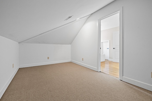 bonus room with lofted ceiling, visible vents, baseboards, and light colored carpet