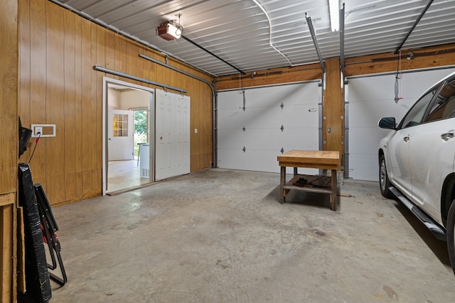 garage with wood walls and a garage door opener