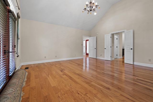 unfurnished bedroom featuring high vaulted ceiling, light wood finished floors, baseboards, and a notable chandelier