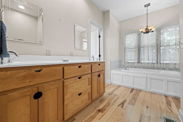 bathroom with double sink vanity, hardwood / wood-style flooring, a notable chandelier, a washtub, and lofted ceiling