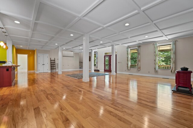 workout area with light wood-type flooring, decorative columns, and coffered ceiling