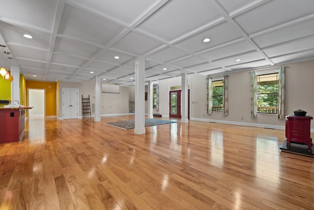 exercise area with light wood-type flooring, coffered ceiling, and baseboards