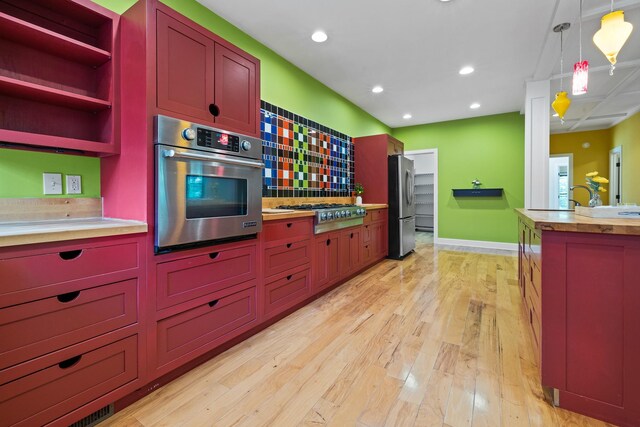 kitchen with decorative light fixtures, light hardwood / wood-style flooring, tasteful backsplash, and stainless steel appliances