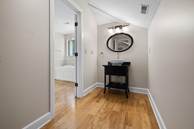 bathroom featuring lofted ceiling, visible vents, vanity, wood finished floors, and baseboards