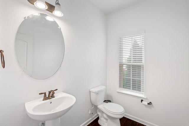 bathroom featuring toilet, a healthy amount of sunlight, and sink