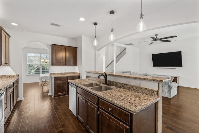 kitchen featuring dark brown cabinetry, sink, hanging light fixtures, stainless steel dishwasher, and a center island with sink