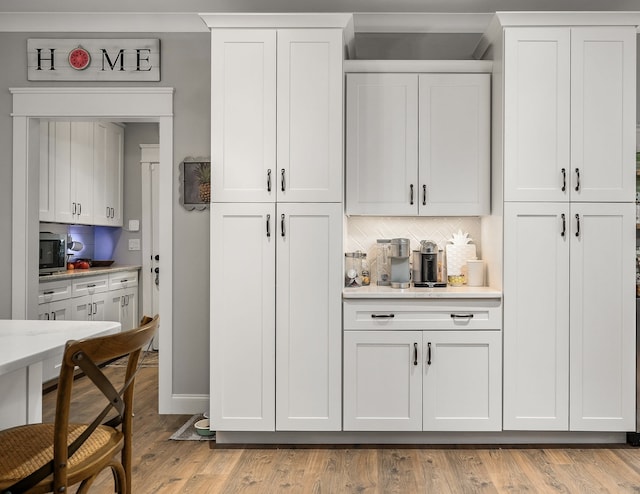 bar featuring decorative backsplash, white cabinets, and light wood-type flooring