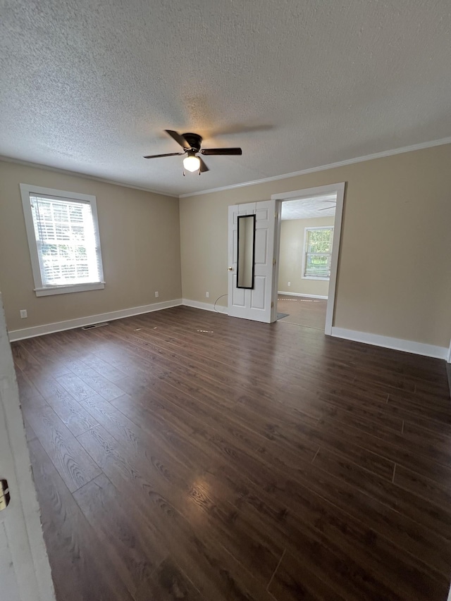 unfurnished room with crown molding, dark wood-style flooring, a ceiling fan, and a healthy amount of sunlight