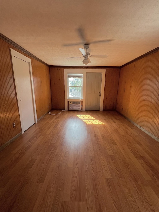 empty room featuring ornamental molding, a wall mounted air conditioner, and wood finished floors