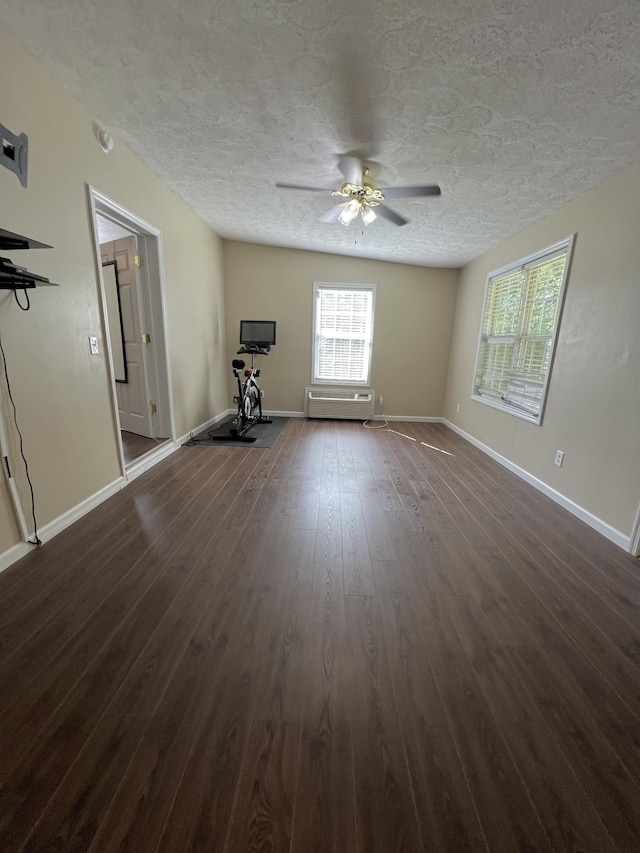 unfurnished living room featuring dark wood-style floors, ceiling fan, a textured ceiling, and baseboards