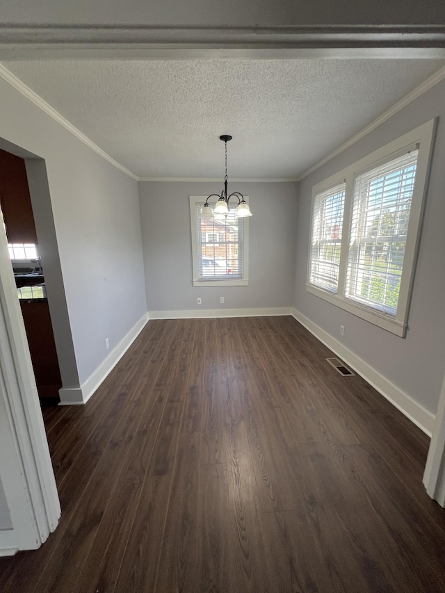 unfurnished dining area with baseboards, ornamental molding, dark wood-style flooring, a textured ceiling, and a chandelier