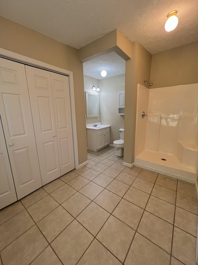 bathroom featuring toilet, vanity, a closet, a shower stall, and tile patterned floors