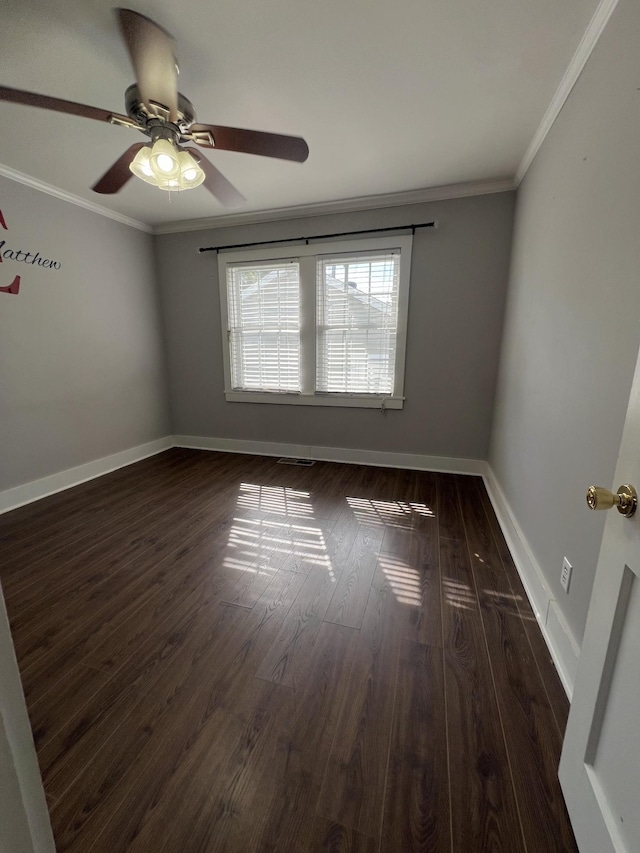 empty room featuring dark wood-style floors, visible vents, baseboards, and crown molding