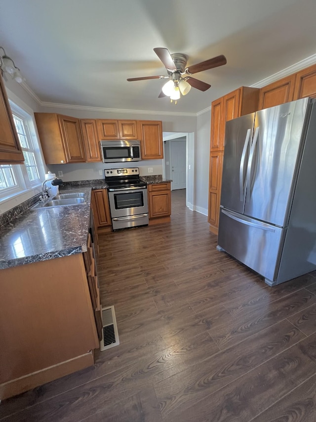 kitchen featuring dark wood-style floors, crown molding, stainless steel appliances, visible vents, and a sink