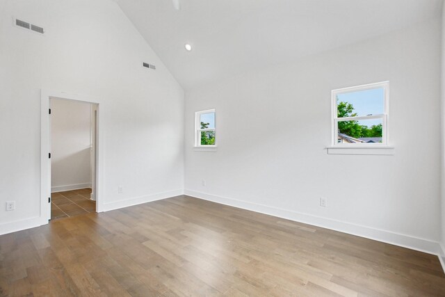 spare room featuring high vaulted ceiling and wood-type flooring