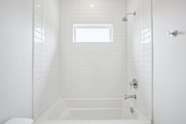 bathroom featuring toilet and tiled shower / bath combo