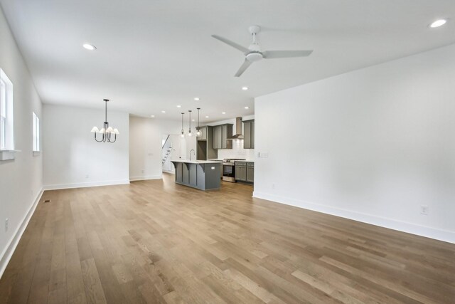 unfurnished living room featuring light hardwood / wood-style floors, ceiling fan with notable chandelier, and sink