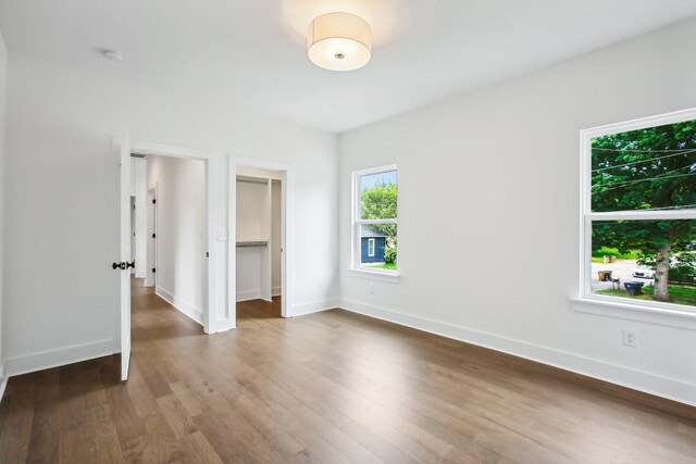 unfurnished bedroom featuring a spacious closet, a closet, and hardwood / wood-style flooring