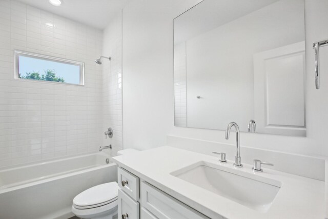 full bathroom featuring vanity, tiled shower / bath combo, and toilet