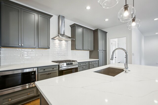 kitchen featuring stainless steel appliances, tasteful backsplash, sink, light stone countertops, and wall chimney range hood