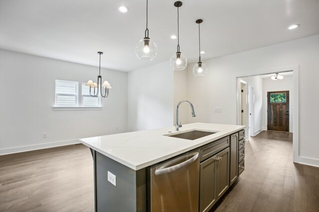 kitchen featuring hardwood / wood-style floors, sink, dishwasher, hanging light fixtures, and a center island with sink