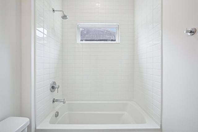 bathroom featuring tiled shower / bath and toilet