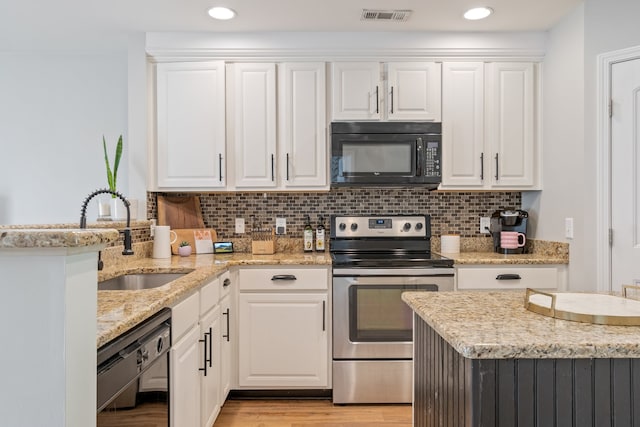 kitchen with light wood-type flooring, white cabinets, and black appliances