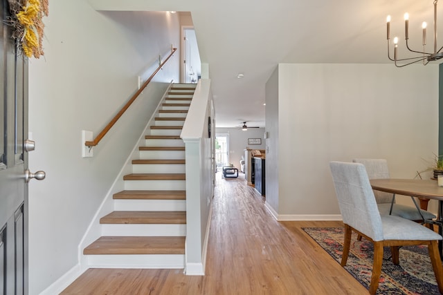 interior space featuring ceiling fan with notable chandelier and light hardwood / wood-style floors