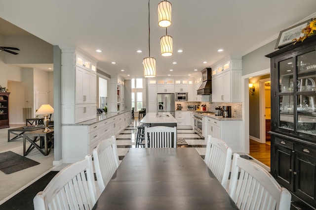 dining room with light hardwood / wood-style flooring, ornamental molding, sink, ornate columns, and ceiling fan