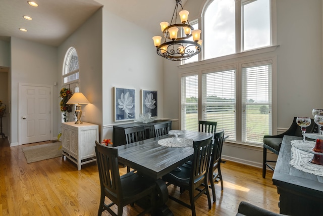 dining area with high vaulted ceiling, an inviting chandelier, and light hardwood / wood-style floors